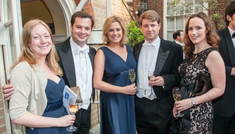 5 people smiling at a camera with champagne